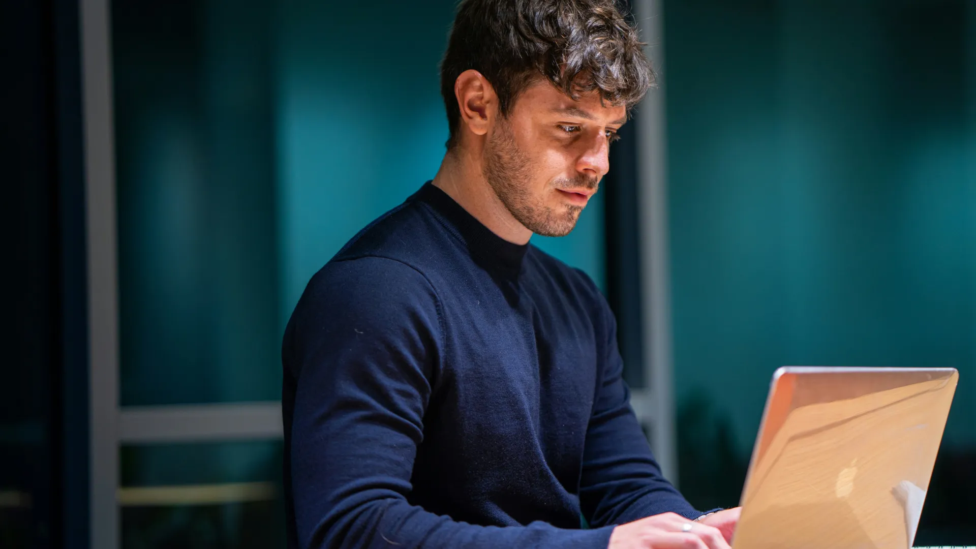 Homem jovem olhando para a tela do notebook.