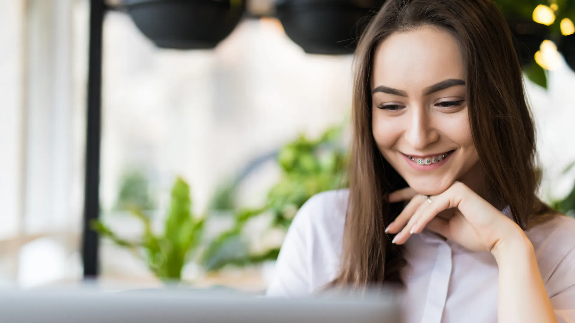 Mulher jovem sorrindo para o conteúdo da tela do computador