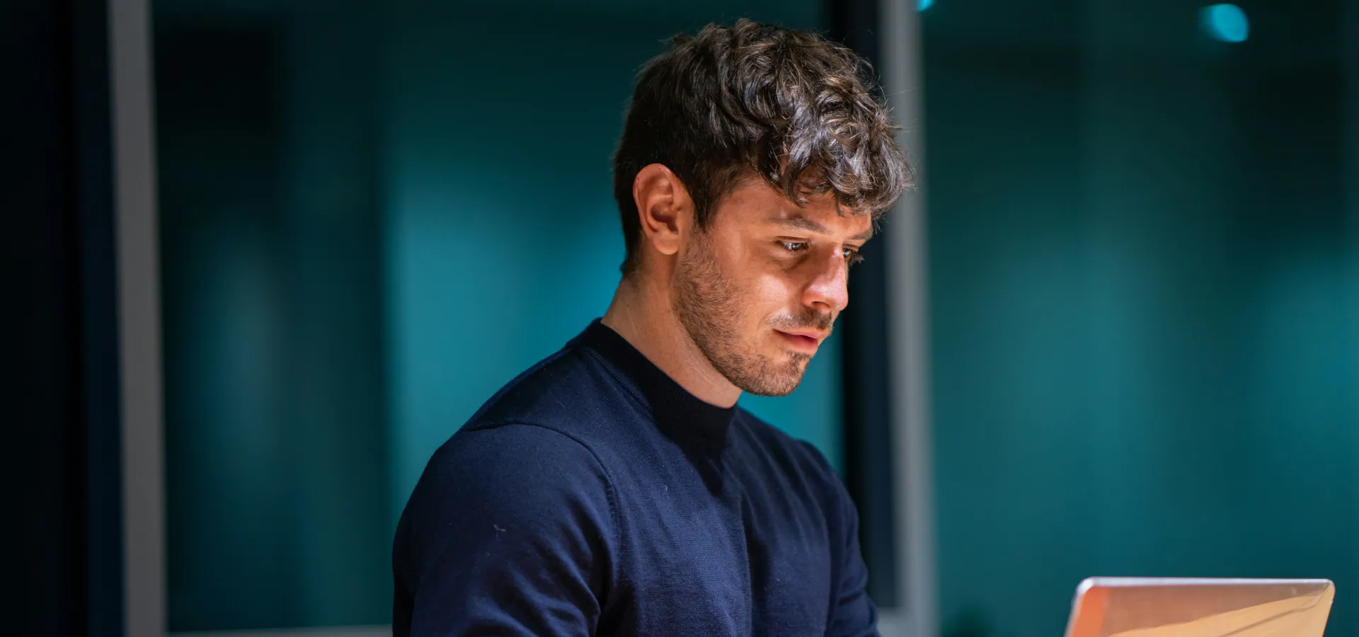 Homem jovem olhando para a tela do notebook.