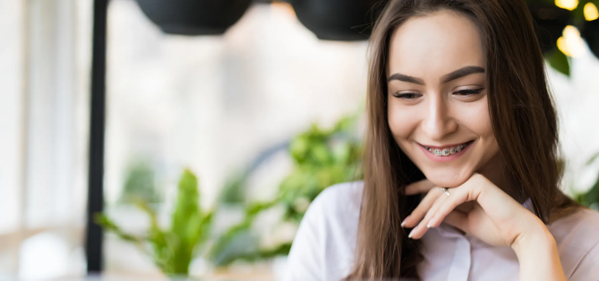 Mulher jovem sorrindo para o conteúdo da tela do computador